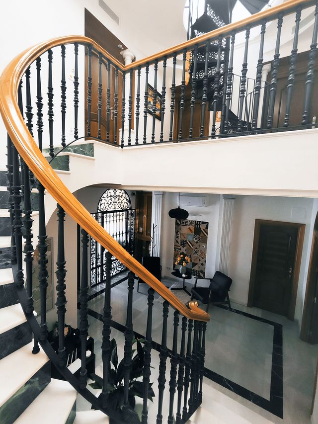Escalera curva con barandilla de forja y pasamanos de madera, vista desde arriba