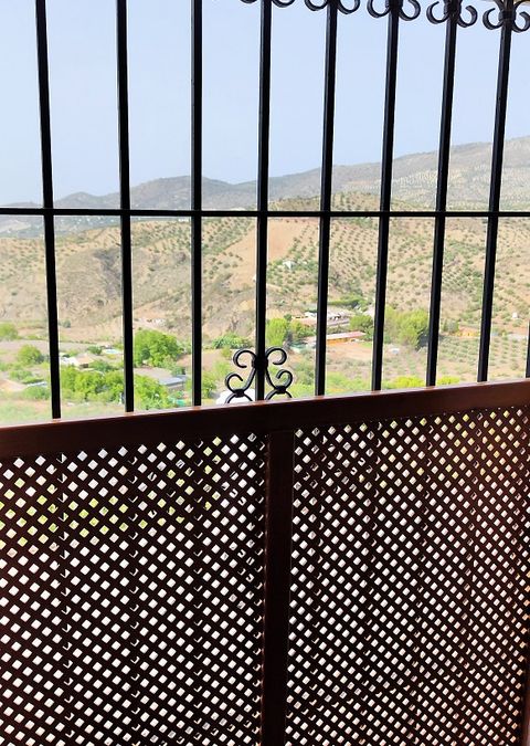Vistas a la vega y las sierras desde la ventana con reja y celosía de madera de la habitación accesible