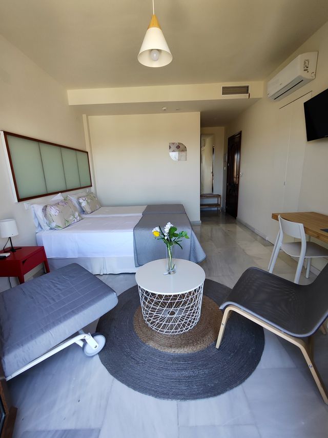 Zona de estar de la habitación, con dos butacas y mesa auxiliar frente a las camas