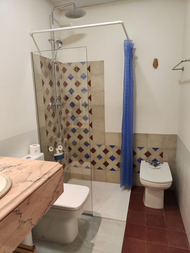 Baño completo con ducha, lavabo sobre encimera de mármol y alicatado de baldosa artesanal