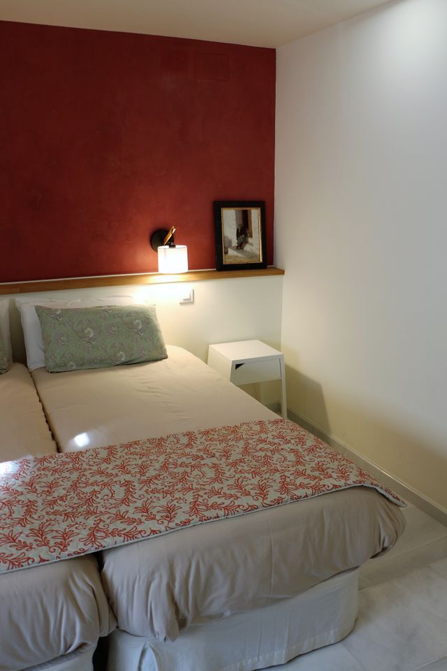 Cama con colcha estampada bajo la pared granate, con aplique de lectura y un cuadro
