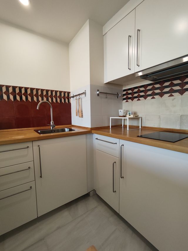 Cocina completa de la suite, con muebles blancos, encimera de madera y fregadero