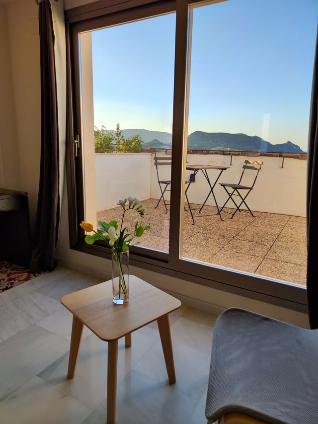 Terraza privada de la suite, con mesa y sillas y vistas a la sierra, vista desde el interior
