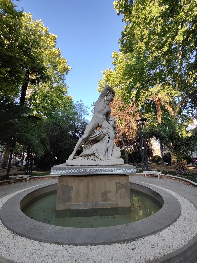Fuente con escultura de mármol blanco en un parque arbolado de Priego