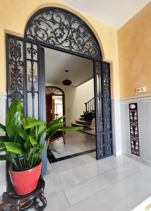 Puerta de entrada con reja de forja en arco y el vestíbulo de la casa al fondo