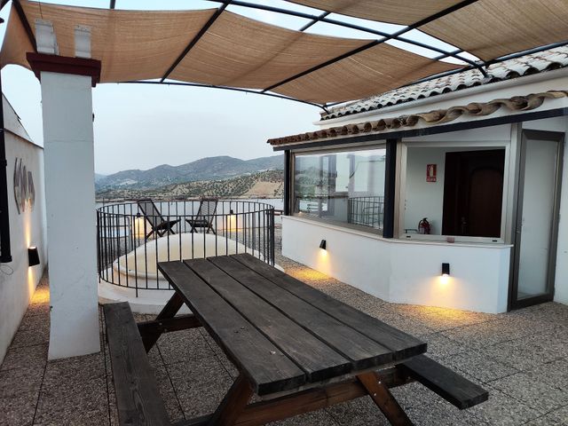 Terraza con mesa de madera bajo una pérgola con cañizo y vistas a la sierra