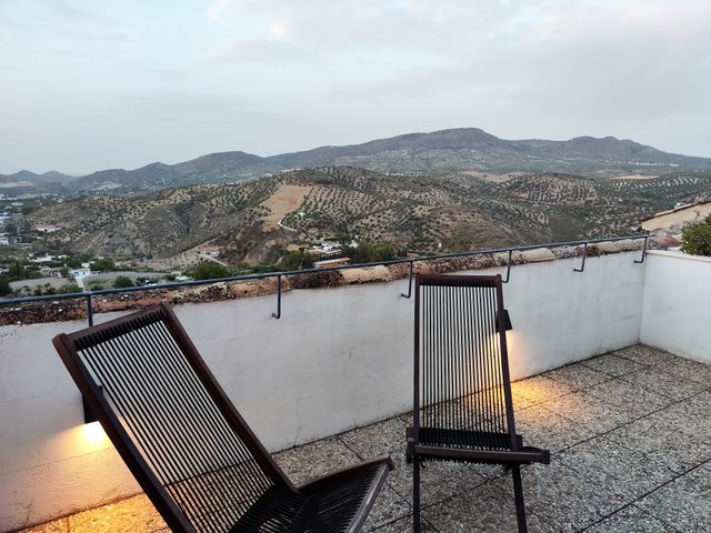 Terraza con dos tumbonas de madera frente a la vega de Priego y las sierras al atardecer